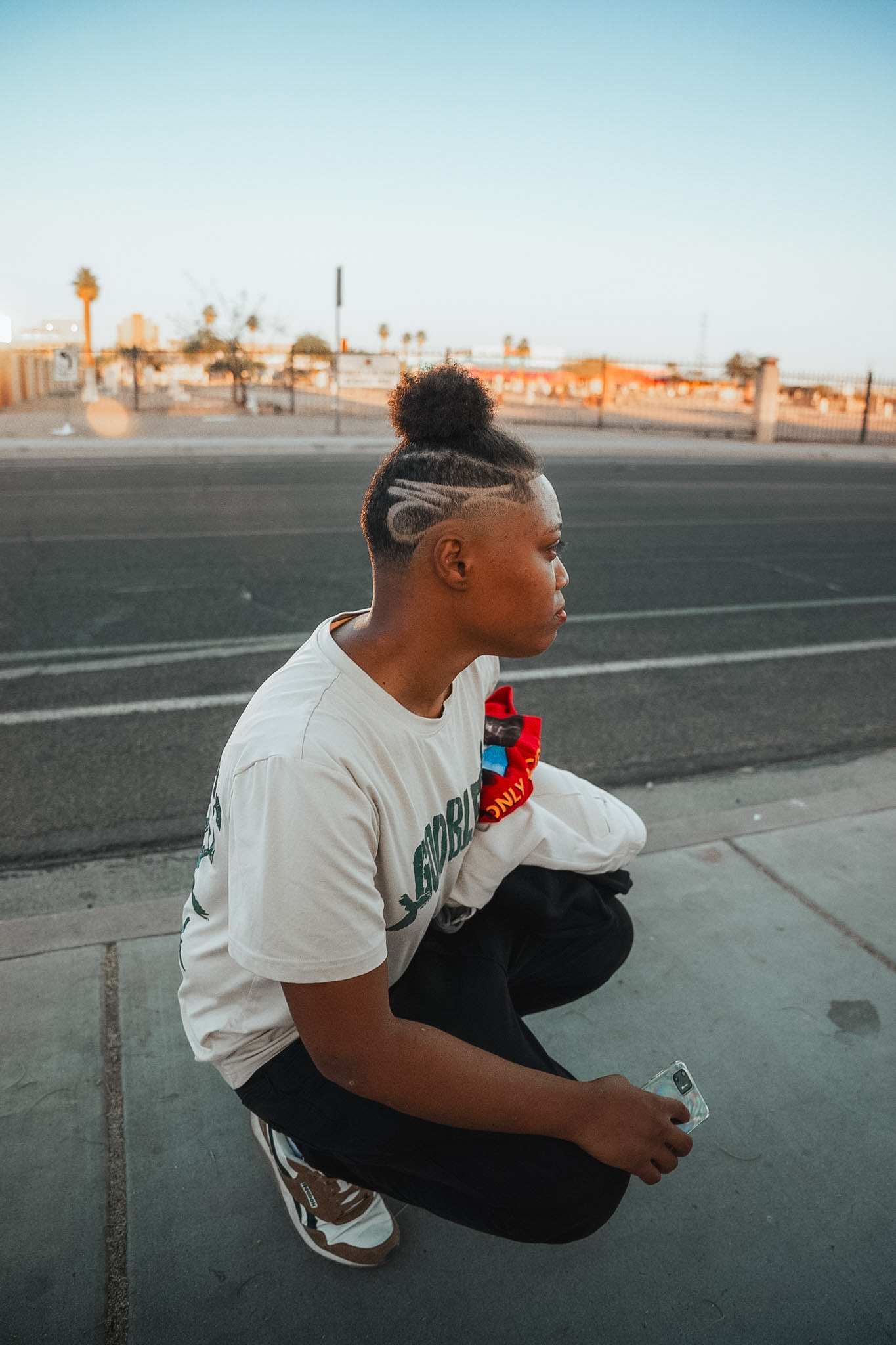 A young man with a freshly cut hair design sitting on the street